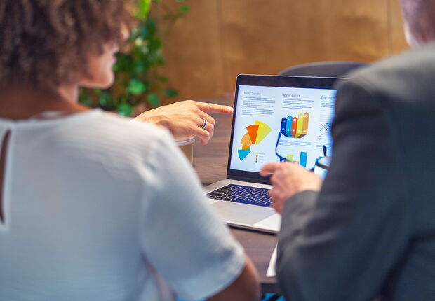 Zwei Personen schauen sich eine Grafik auf einem Laptop an